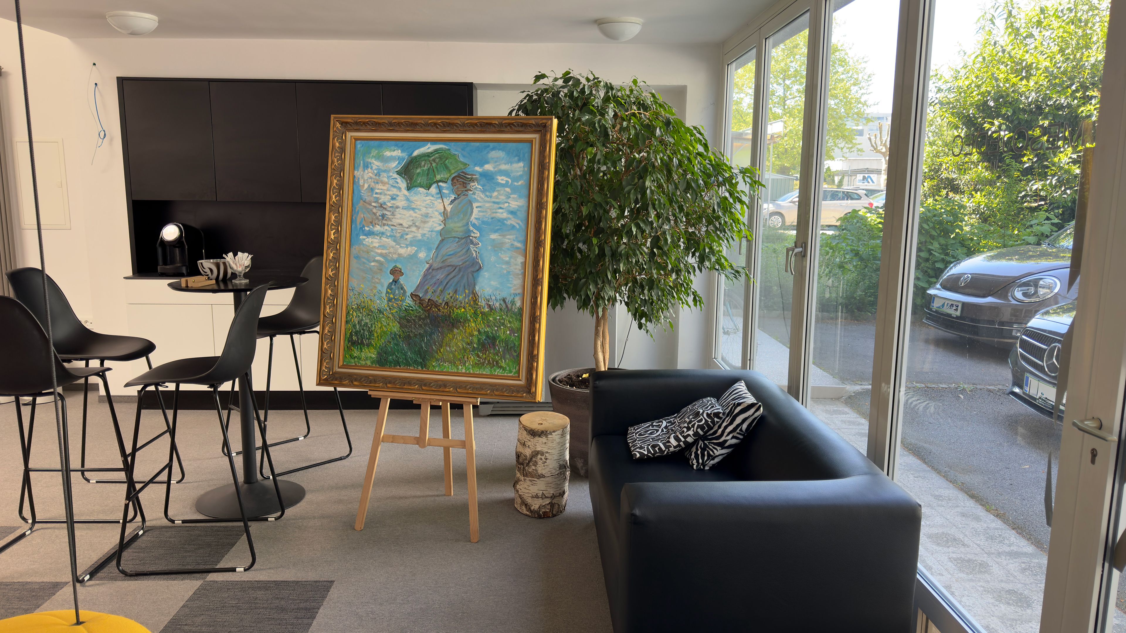 Uokvirjena ročno naslikana reprodukcija: Claude Monet, Žena z dežnikom, razstavljena na stojalu v prostoru